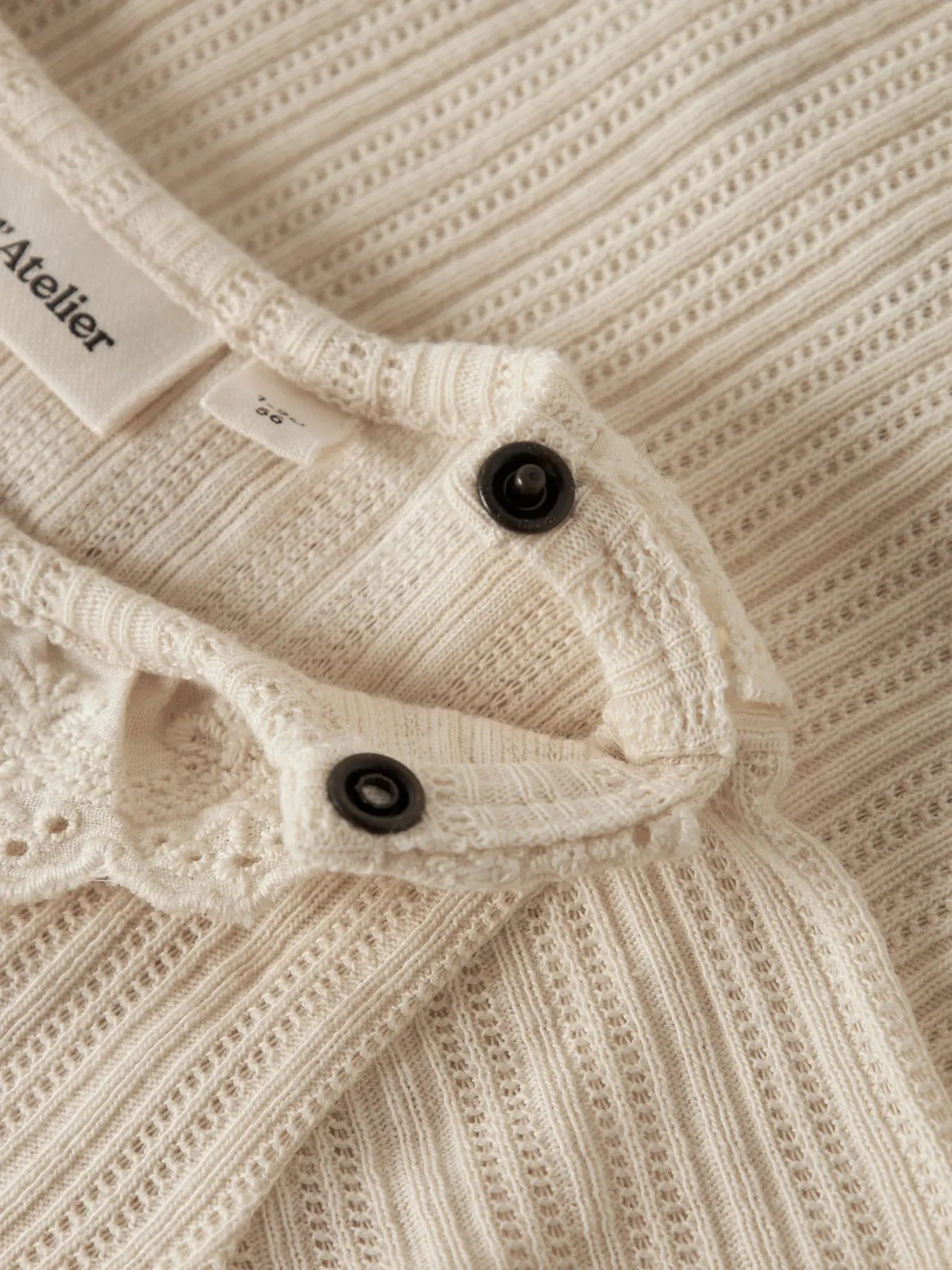 Detalj av blondekrage, trykknapper og stoff på Lil’ Atelier Eluva body i Turtledove